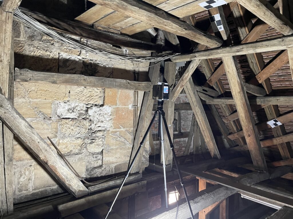 Terrestrial laser scanner on a tripod inside a historic timber roof structure