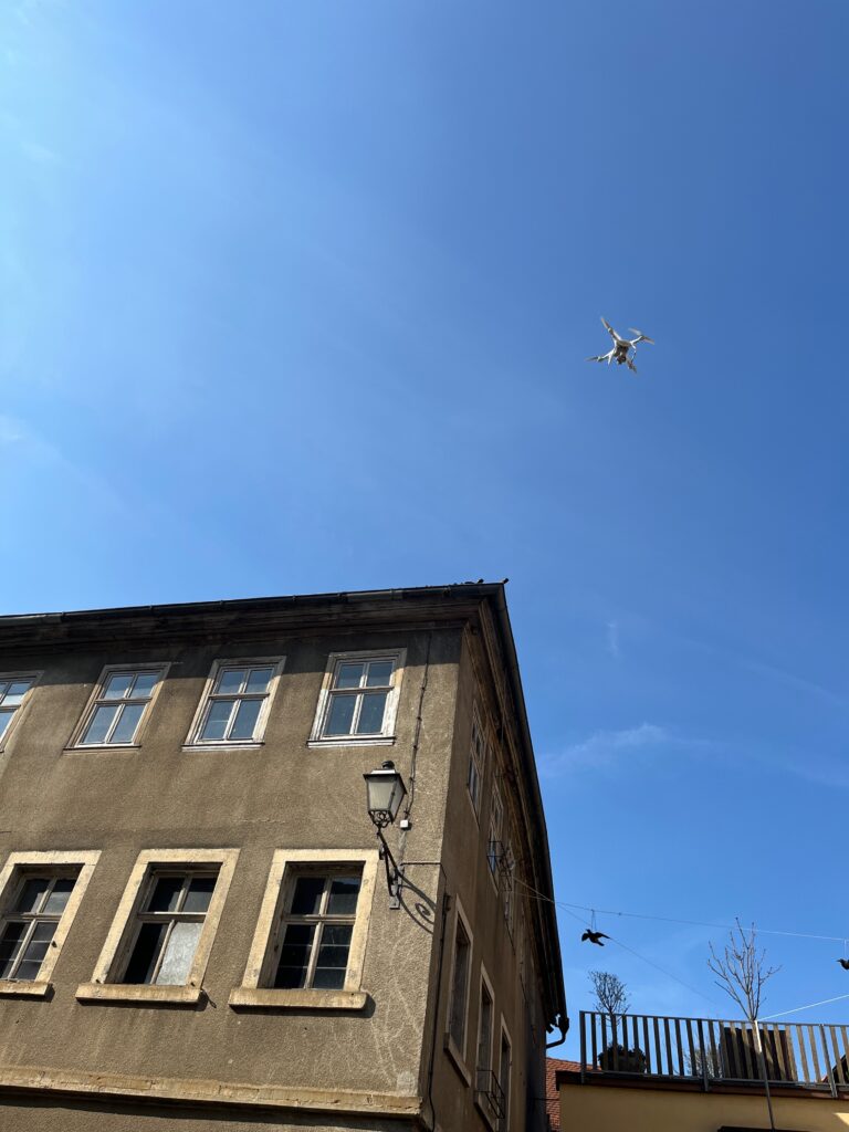 Drone flying above the facade of a rendered building against a clear sky