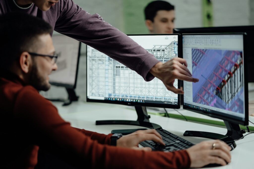 Modeller at a workstation with two screens showing a building model